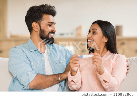 Excited indian couple looking at pregnancy test 110952963