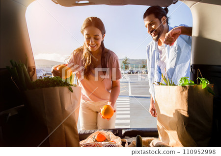 Arab couple admiring groceries in trunk during sunset 110952998