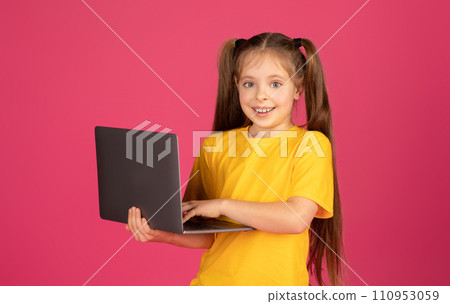 Portrait Of Cute Little Girl Holding Laptop Computer And Looking At Camera Portrait Of Cute Little Girl Holding Laptop Computer And Looking At Camera 110953059