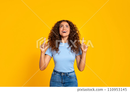 Joyful woman pointing up on a yellow background Joyful woman pointing up on a yellow background 110953145