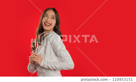 Young woman raising sparkling wine glass on red studio background Young woman raising sparkling wine glass on red studio background 110953151
