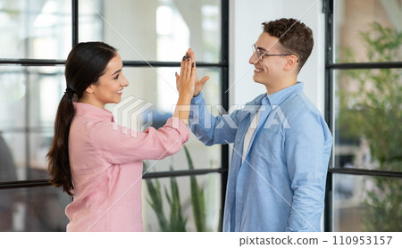 Glad millennial arab lady and european guy manager giving high five with hands 110953157