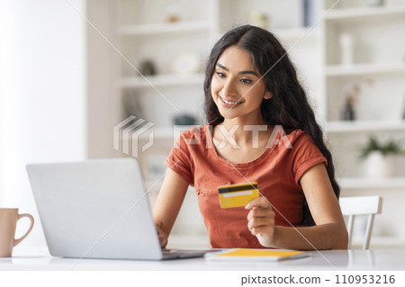 Young woman holding credit card and using laptop 110953216