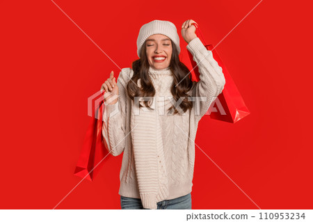 Happy lady buyer holds shopping bags posing on red backdrop 110953234