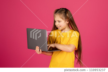 Portrait of curious preteen girl using laptop while standing on pink background Portrait of curious preteen girl using laptop while standing on pink background 110953237