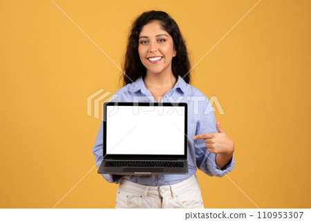 Happy latin millennial brunette lady in casual point finger at laptop with empty screen 110953307