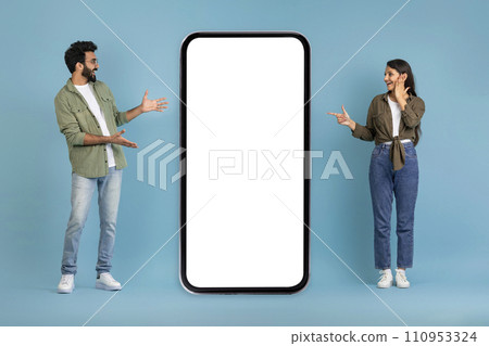 Amazed indian lovers pointing at big phone with white screen Amazed indian lovers pointing at big phone with white screen 110953324