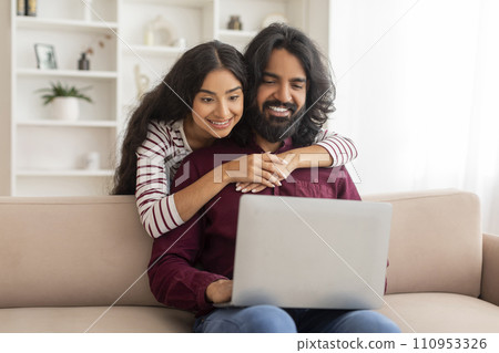 Loving indian spouses shopping on Internet from home, using computer 110953326