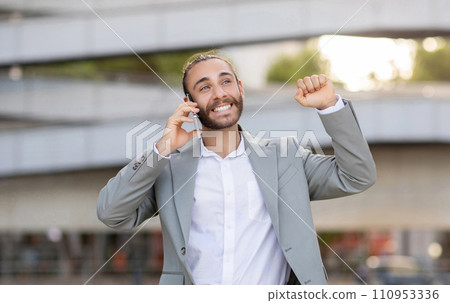 Joyful young businessman celebrating success during outdoor phone call Joyful young businessman celebrating success during outdoor phone call 110953336