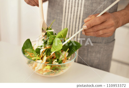 Unrecognizable black guy mixes fresh vegetables ingredients making salad indoor 110953372