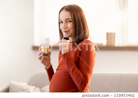 Young pregnant lady enjoys tasty snack eating sweet dessert indoors Young pregnant lady enjoys tasty snack eating sweet dessert indoors 110953402
