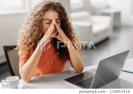 Stressed woman with eyes closed touching nose in front of laptop 110953418