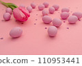 Easter card. Bright pink chocolate eggs scattered on pink background. Shimmering glowing hearts and delicate tulip. Easter and spring themes, use in marketing materials, packaging. Happy holidays 110953441