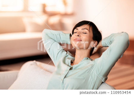 Middle aged woman leaning back on her sofa at home 110953454