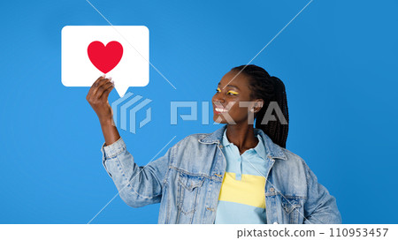 Joyful black millennial woman showcasing social media like, blue background 110953457
