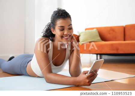 woman enjoys relaxing break browsing through smartphone in living room 110953523