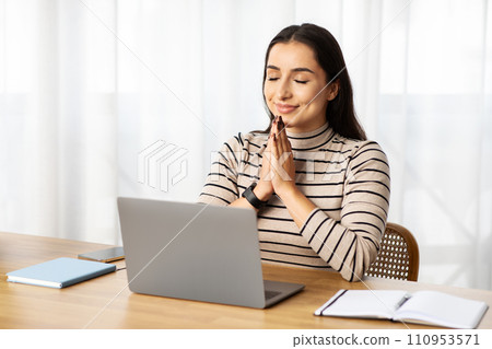 Positive young arab lady manager work at computer, make pray gesture, expect good news Positive young arab lady manager work at computer, make pray gesture, expect good news 110953571