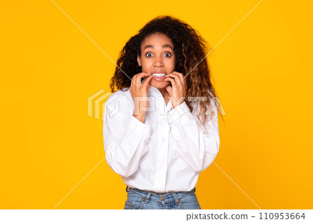 Worried young black lady expressing fear and anxiety, yellow background 110953664