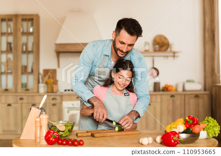 Dad teaches daughter to cut veggies 110953665