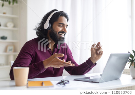 Portrait Of Smiling Indian Man In Headset Making Video Call With Laptop 110953703