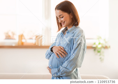 Pregnant european woman touches and hugs her belly at home 110953736