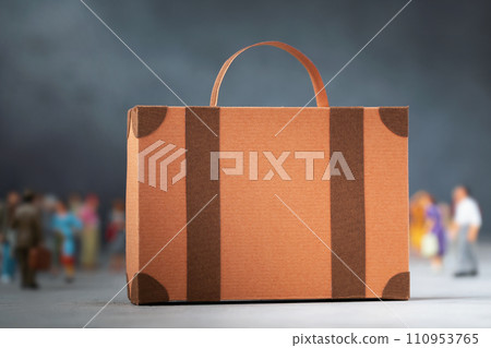 Cardboard suitcase and out of focus plastic toy men on an abstract background, concept on the theme of moving or migration, template for designer 110953765