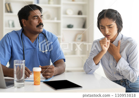 Sick Young Indian Woman Coughing During Meeting With Male Doctor In Clinic 110953818