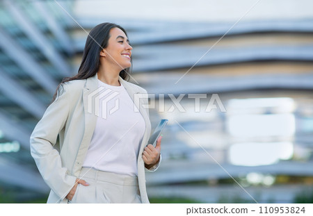 Hispanic business lady standing on city street near office center 110953824
