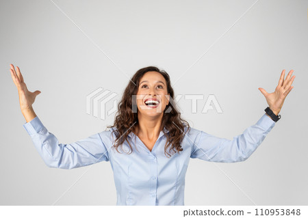 Happy excited young european lady in formal wear with open mouth rise hands up, hold free space Happy excited young european lady in formal wear with open mouth rise hands up, hold free space 110953848
