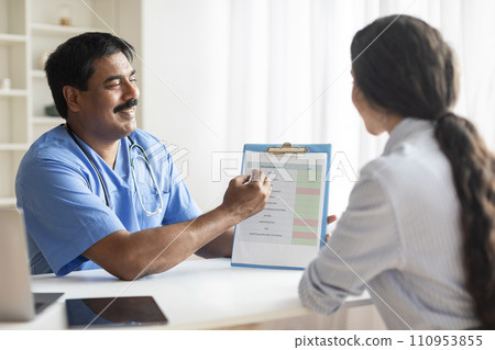 Indian Doctor Man Showing Clipboard With Medical Test Form To Female Patient 110953855
