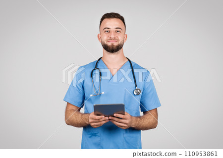 Smiling male doctor with tablet, blue coat, grey background Smiling male doctor with tablet, blue coat, grey background 110953861