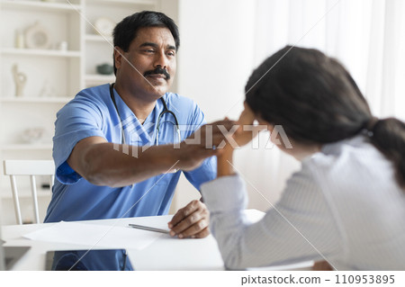 Mature Indian Doctor Man Comforting Depressed Female Patient During Appointment In Clinic 110953895