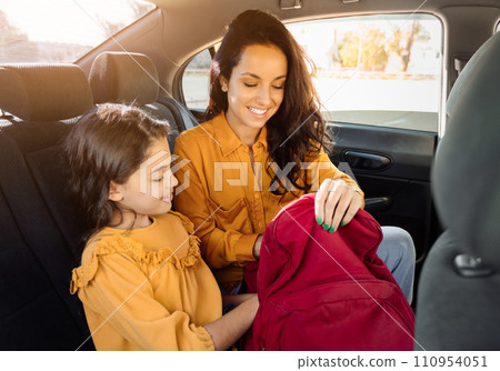 Smiling mother and daughter in car, examining red bag together 110954051