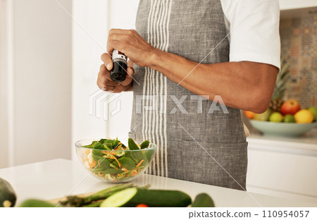 Unrecognizable African American man seasoning vegetable salad with pepper indoor 110954057
