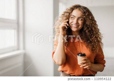 Joyful woman on call with coffee cup 110954122