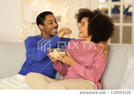 African spouses having movie night sharing popcorn at home 110954126