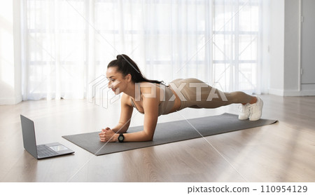 Young woman have workout at home, using laptop Young woman have workout at home, using laptop 110954129