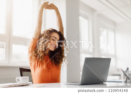 Relaxed woman stretching at her desk with laptop, copy space Relaxed woman stretching at her desk with laptop, copy space 110954148