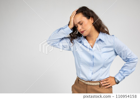 Upset tired millennial caucasian lady, with pained expression, clutching at head 110954158