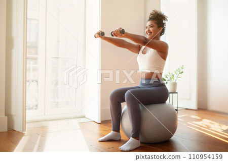 lady performs arm workout holding dumbbells using balance ball indoor lady performs arm workout holding dumbbells using balance ball indoor 110954159