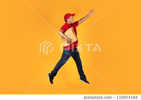 Arab deliveryman leaping with cardboard box over yellow studio background 110954168