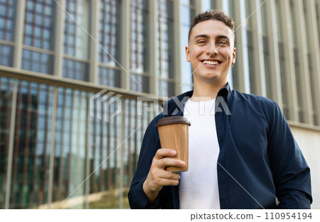 Glad handsome millennial caucasian man student manager enjoy coffee break with cup of drink Glad handsome millennial caucasian man student manager enjoy coffee break with cup of drink 110954194