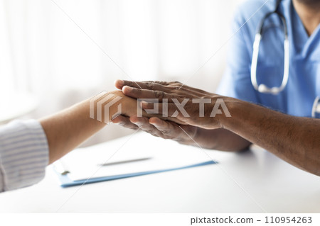 Closeup Of Doctor Holding Hand Of Female Patient During Meeting In Office 110954263