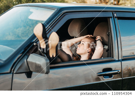 sexy girl driving a car. the girl pulled her legs out of the car window. sexy legs in pantyhose 110954304