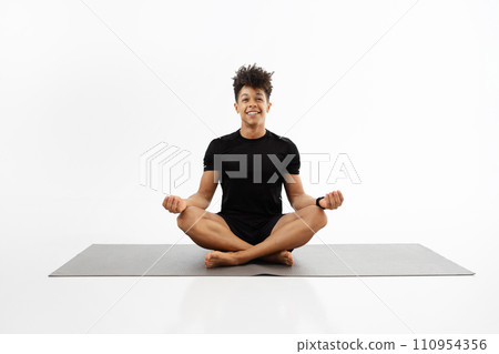 fitness guy practices yoga sitting in lotus position, white background 110954356