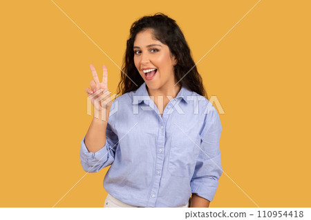 Glad latin millennial brunette lady in casual show peace sign with hand, enjoy lifestyle 110954418