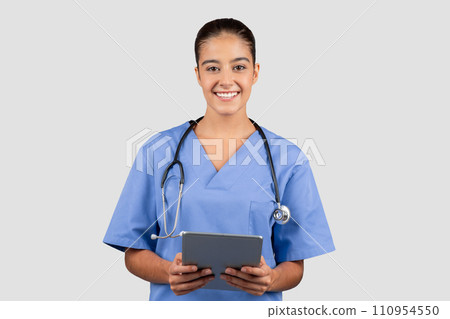 Happy confident european millennial woman doctor or nurse in blue uniform with tablet Happy confident european millennial woman doctor or nurse in blue uniform with tablet 110954550