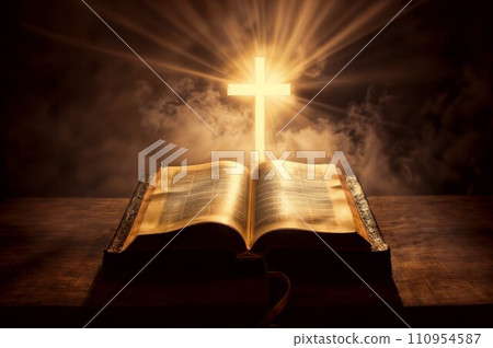 An open Bible with a cross above it, all set against a smoky black background. 110954587