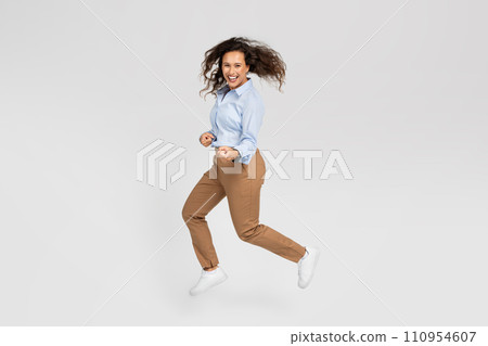 Glad excited young caucasian woman enjoy win, good mood, jump, freeze in air, point fingers to camera 110954607