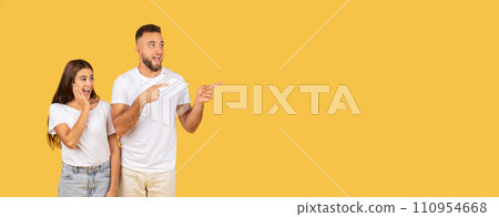 Cheerful shocked young european man in casual and lady point finger at free space Cheerful shocked young european man in casual and lady point finger at free space 110954668